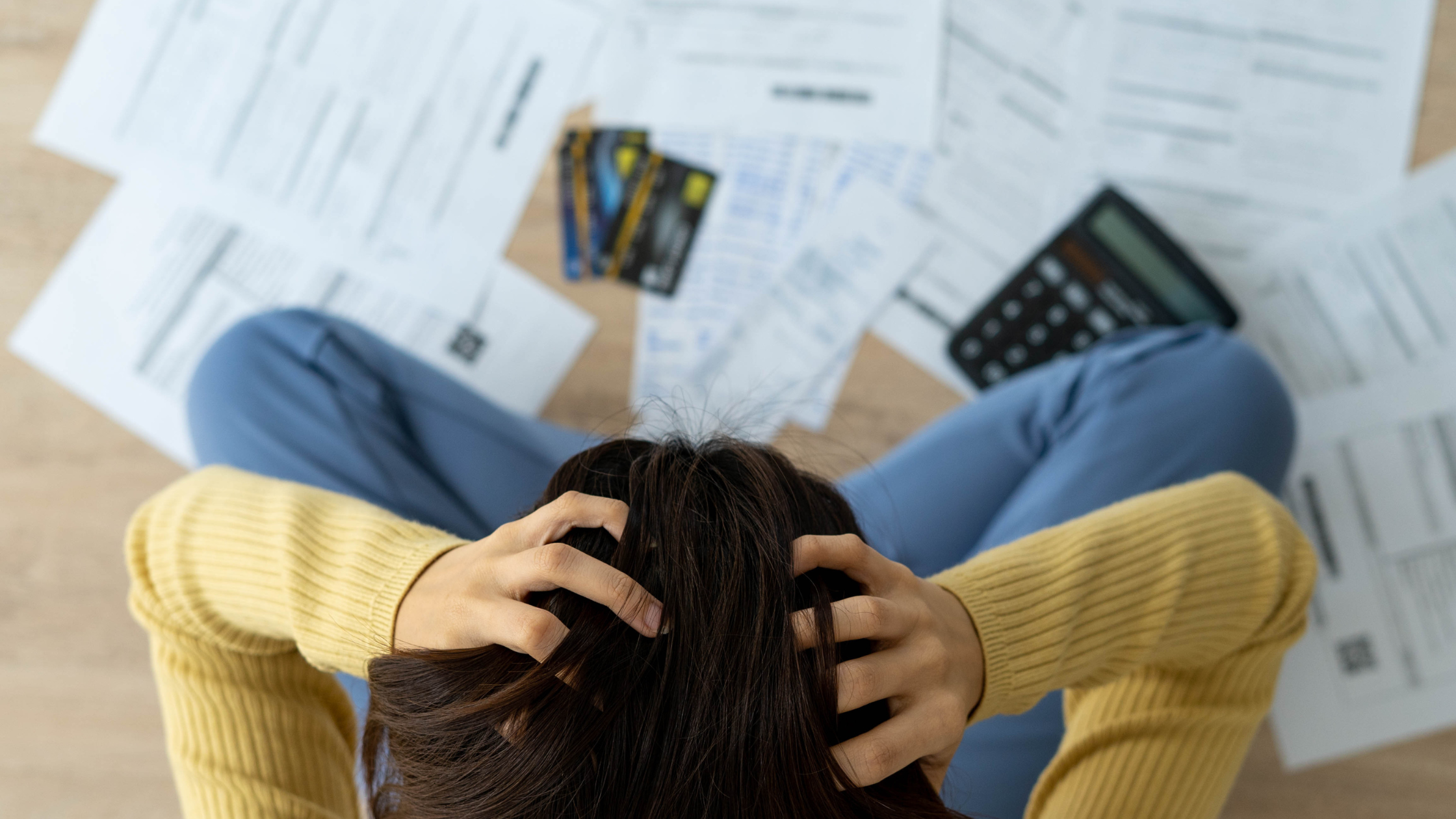 priority management blog post image of woman holding head staring at bills