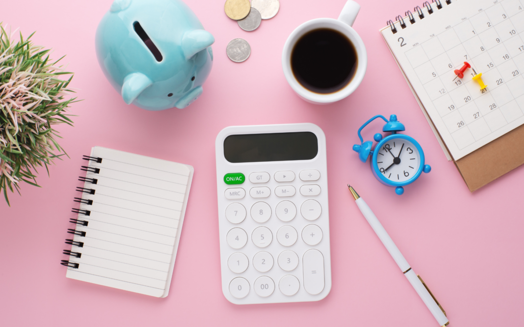 overhead shot of calculator coffee cup piggy bank notebook and calendar and pen