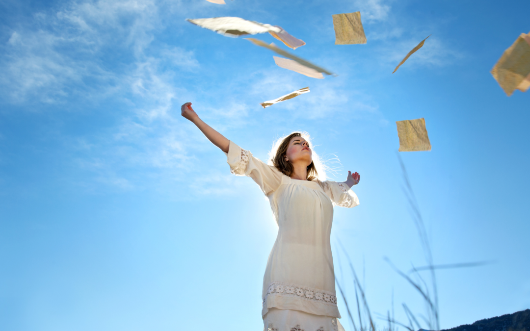 woman standing with arms up with papers flying in the air